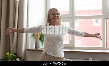 Felice donna matura in piedi con le braccia tese, godersi la vita Foto Stock