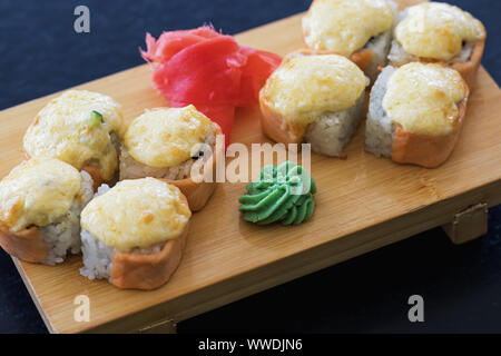 Panini caldi con lo zenzero, wasabi e il salmone in un supporto di legno. La deliziosa cucina giapponese Foto Stock