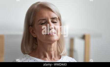 Close up tranquillo e pacifico donna matura rilassante con gli occhi chiusi Foto Stock