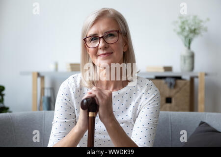 Colpo alla testa ritratto bella donna più anziana in bicchieri con canna Foto Stock