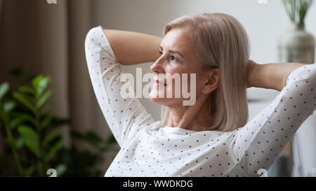 Trasognata donna matura rilassante schiena pendente, pensando al futuro Foto Stock
