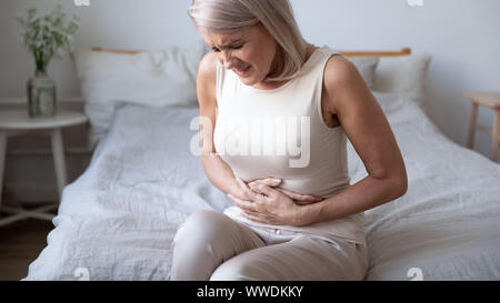 Malsana donna matura azienda ventre, che soffrono di dolore Foto Stock