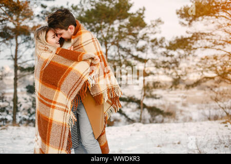 Coppia felice avvolto in una coperta in piedi nel parco in un giorno di neve Foto Stock