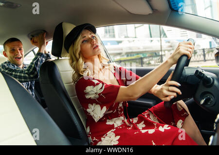 Foto di donna autista guida e passeggero maschio di equitazione in auto durante il giorno Foto Stock