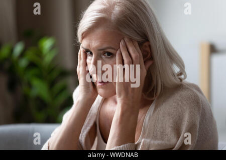 Sconvolto donna anziana toccando i templi, sensazione di cattivo, disordine mentale Foto Stock