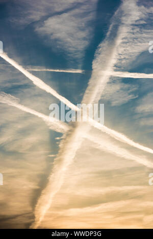 Molti sentieri di vapore da velivoli passeggeri attraversano il cielo di sera al di sopra di Zurigo, Svizzera, durante il tramonto. Foto Stock