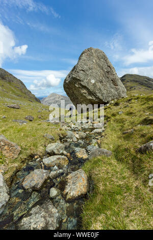 Hill-walker in piedi accanto a un enorme masso, Fionna Choire, Blaven, Isola di Skye, Scotland, Regno Unito Foto Stock
