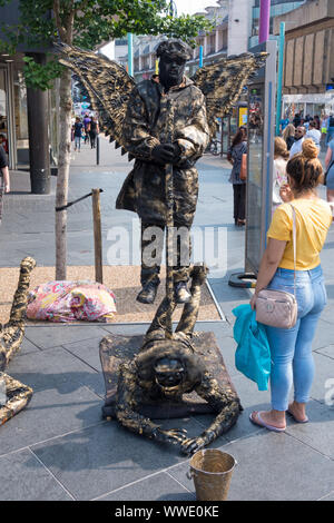 Che sfidano la forza di gravità floating angelo statua vivente street artista in Leicester City Centre, Leicester, England, Regno Unito Foto Stock