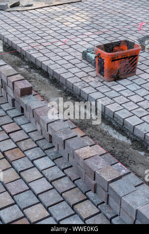 Righe di nuovo blocco lastricatore marciapiede essendo prevista nella zona pedonale della città di Leicester, England, Regno Unito Foto Stock