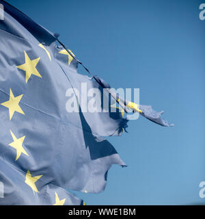 Unione europea dodici stelle bandiera strappata e con nodi di vento sul cielo blu, sfondo vicino. Flag è strappato a lato, simbolo di problemi, decadenza, dis Foto Stock