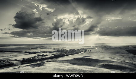 Un fiume che si snoda attraverso boschi verso il bel sunray di un sole di setting come grandi nuvole raccogliere overhead. Foto Stock