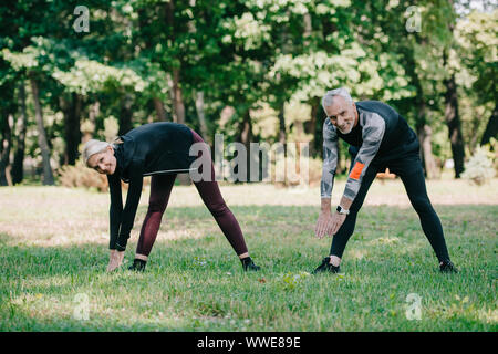 Allegro, maturo sportivo e sportive sorridente in telecamera mentre la formazione in posizione di parcheggio Foto Stock