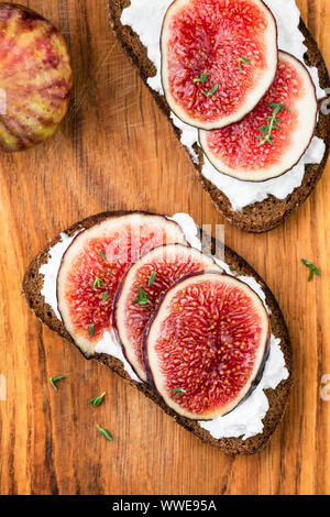 Fichi e ricotta pane di segale tostato. Sana sandwich saporiti su sfondo di legno Foto Stock