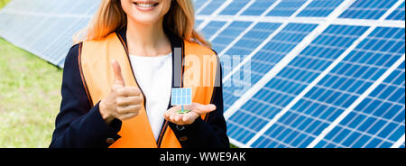 Panoramica di imprenditrice nel giubbotto di sicurezza azienda solar modello di batteria Foto Stock