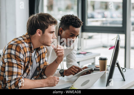 Americano africano utilizzando il programmatore digitale compressa mentre si lavora con un collega in ufficio Foto Stock