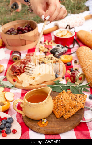Elegante pic nic sul prato verde. Cornetti freschi e una teiera con il tè su un copriletto vicino a una femmina di vimini hat. Instagram contenuto. Foto Stock