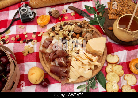 Elegante pic nic sul prato verde. Cornetti freschi e una teiera con il tè su un copriletto vicino a una femmina di vimini hat. Instagram contenuto. Foto Stock