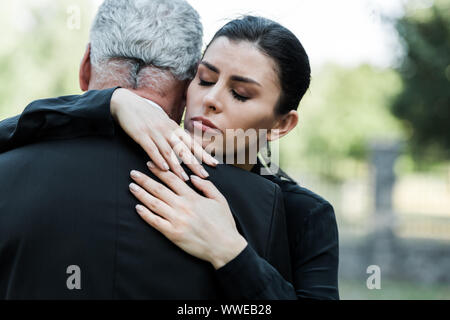 Turbare la donna con gli occhi chiusi abbracciando uomo senior Foto Stock