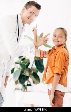 Sorridente pédiatre in camice bianco e il bambino in clinica Foto Stock