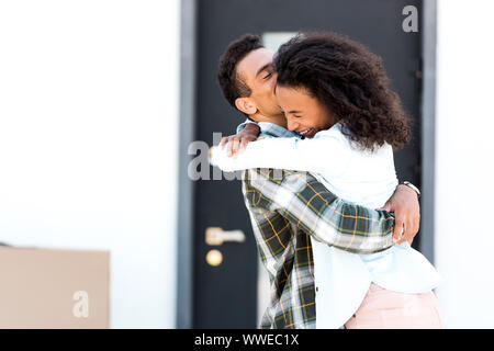 African American giovane rideva mentre il marito moglie tenuta in mano e Donna sorridente con gli occhi chiusi Foto Stock