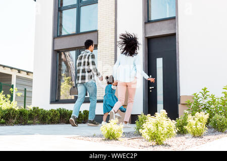 Lunghezza piena vista della famiglia americana africana in esecuzione per la nuova casa Foto Stock