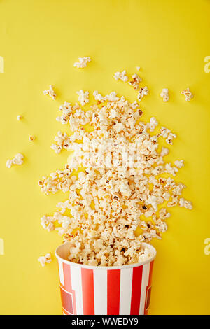 Vista dall'alto di deliziosi popcorn diffusa dalla benna su sfondo giallo Foto Stock