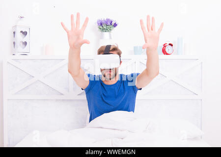 La migliore esperienza di VR. Bel ragazzo indossa le cuffie VR a letto. Uomo caucasico utilizzando occhiali VR in camera da letto. Il rendering di coinvolgente in VR. Foto Stock