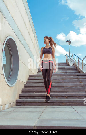 Una bella ragazza top sport gambali, passeggiate scale estate città un jog di mattina e uno stile di vita attivo dei giovani. Idoneità a piedi, allenamento, slim conciate Foto Stock