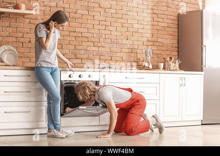 Lavoratore riparazione di forno in cucina Foto Stock