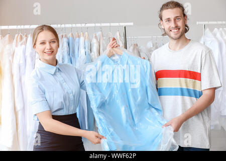 Lavoratore dando vestiti a client in moderno a secco del filtro Foto Stock