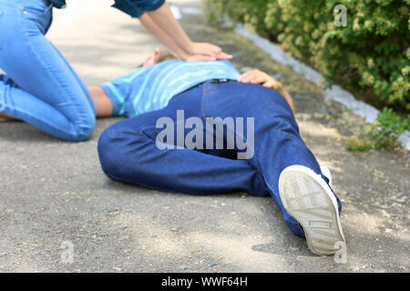 Donna che CPR inconscio l uomo all'aperto Foto Stock
