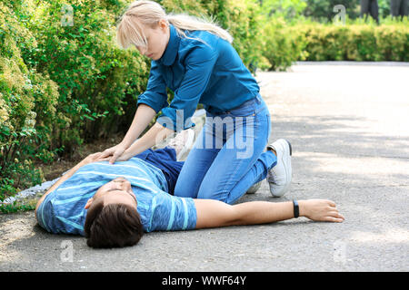Donna che CPR inconscio l uomo all'aperto Foto Stock