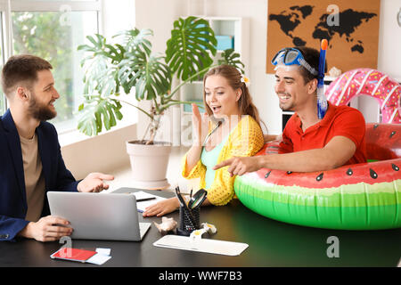 Maschio di agente di viaggi lavora con coppia giovane in office Foto Stock