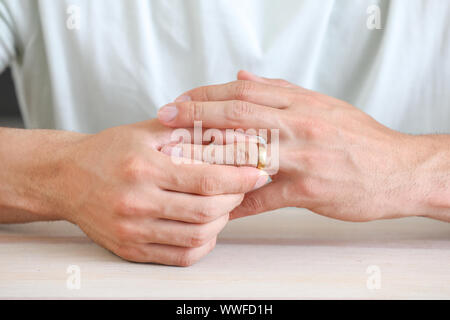 L'uomo tenendo fuori il suo anello di nozze a casa closeup. Concetto di divorzio Foto Stock