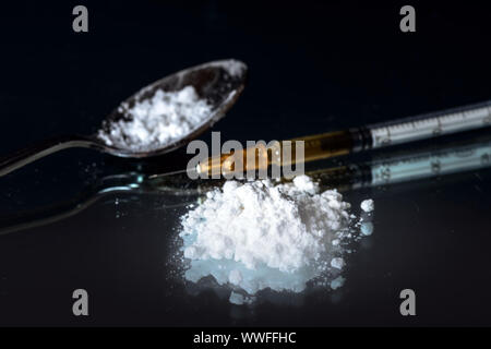 Polvere bianca, la siringa e il farmaco su cucchiaio. Dipendenza da narcotici concetto. Nero lo sfondo dello specchio Foto Stock