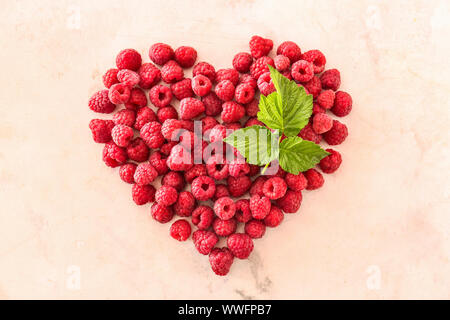 Forma di cuore fatta di lamponi freschi su sfondo chiaro Foto Stock