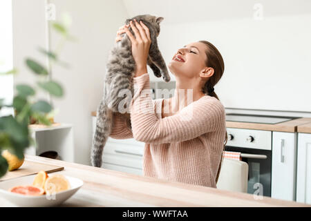 Bella giovane donna con cute cat in cucina Foto Stock