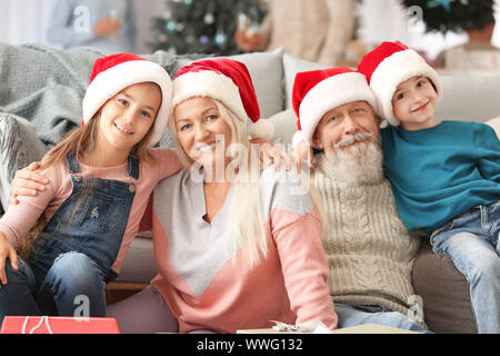 Felici i nonni e i bambini piccoli in Santa Claus cappelli a casa Foto Stock