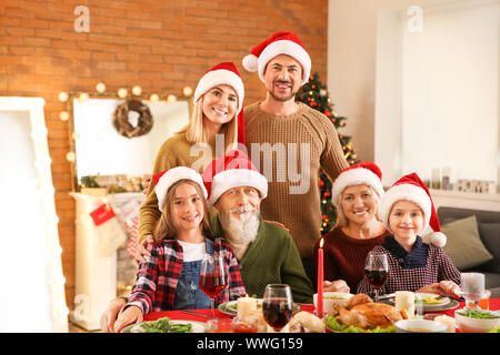 La famiglia felice in Santa Claus cappelli festeggia il Natale a casa Foto Stock