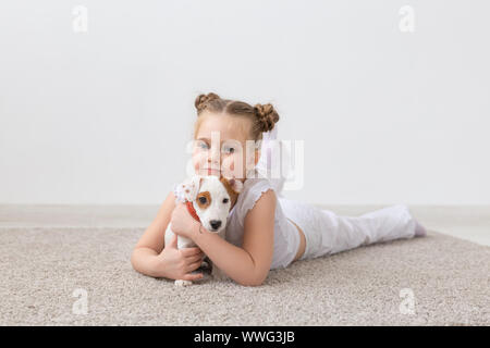 Persone, bambini e animali domestici concetto - bambino ragazza distesa sul pavimento con grazioso cucciolo Foto Stock