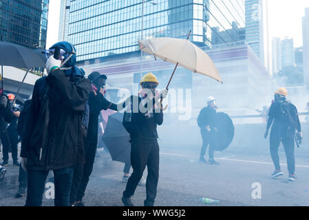 Hong Kong. Xv Sep, 2019. Manifestanti face off contro la polizia di fronte agli uffici del governo come gas lacrimogeni riempie l'aria durante la dimostrazione.Migliaia di manifestanti hanno marciato per le strade del XV Settimana continuo di disordini. Mentre la dimostrazione ha iniziato pacificamente, manifestanti più tardi di fronte contro la polizia di fronte agli uffici del governo. I manifestanti hanno gettato mattoni e bombe a benzina mentre la polizia ha cercato di mantenere i dimostranti al bay da sparo decine di gas lacrimogeni turni e contundenti. Sommossa polizia eventualmente distribuito sui veicoli equipaggiati con acqua di cannoni e condotto una piena dis Foto Stock