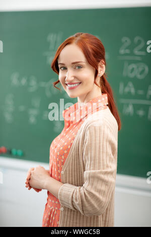 I capelli rossi insegnante di matematica in piedi vicino a lavagna in aula Foto Stock