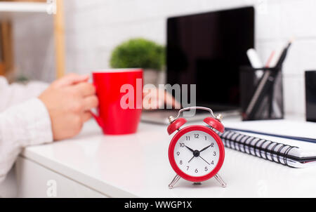 Sveglia rossa e la mattina caffè sulla tabella di office Foto Stock