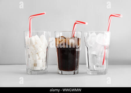 Occhiali con cola, zucchero e ghiaccio sul tavolo luminoso Foto Stock