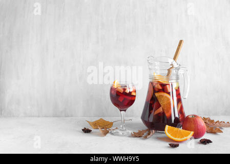 In autunno la Sangria o punzone nella brocca. In casa il vino rosso frutto sangria e giallo foglie autunnali su sfondo bianco, copia dello spazio. Foto Stock