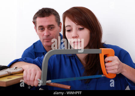 Apprendista femmina plumber segare il tubo in rame Foto Stock