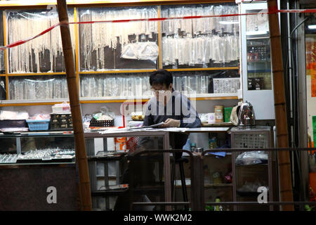 HONG KONG - dic 7, un bottegaio si concentra nella lettura di un giornale di Hong Kong il 7 dicembre, 2010. Egli è un tipico di Hong Kong hawker. Foto Stock