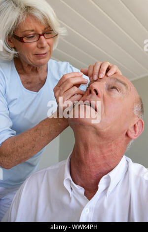 Donna aiutando il marito con le lenti a contatto Foto Stock