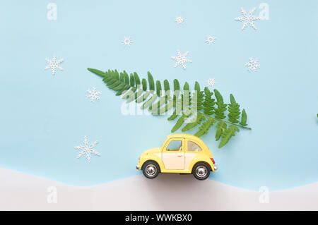 Il verde albero di Natale su giallo giocattolo auto con i fiocchi di neve. xmas holiday celebrazione il concetto di copia vuota dello spazio per l'iscrizione. Sfondo di vacanza Foto Stock