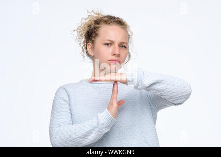 Blonde insoddisfatto curly donna in blu maglione rendendo time out gesto Foto Stock